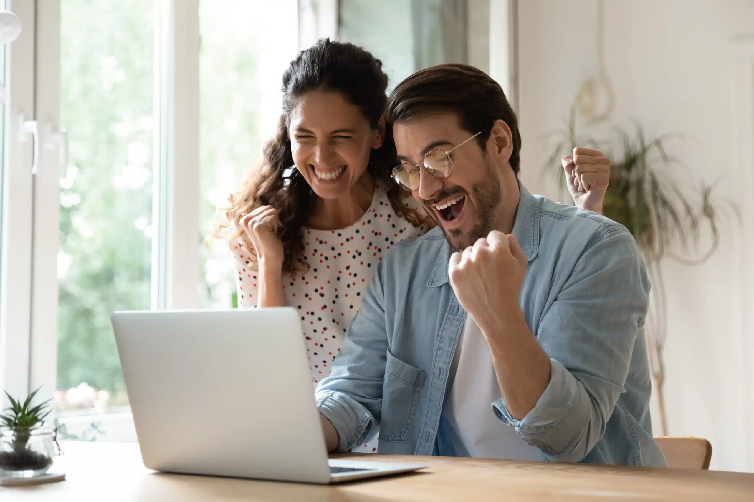 Excited couple staring at the approval for their mortgage on a laptop
