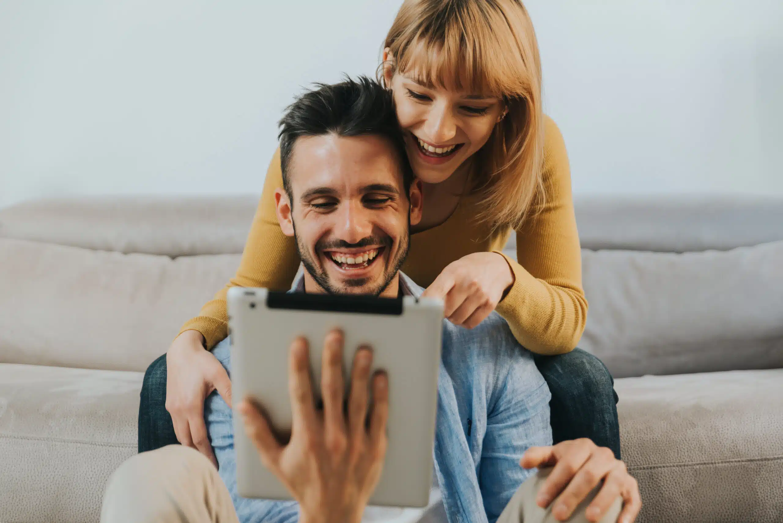 Un couple heureux regarde une tablette avec les incitations à l'achat d'un logement qui leur sont offertes.